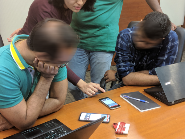 Photograph of team discussing UX/UI design interactions in mobile app prototype with clients